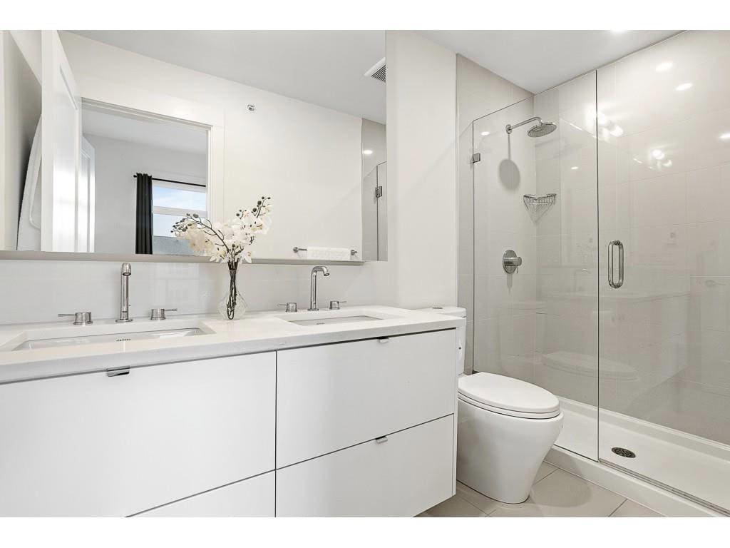 Modern white bathroom with dual sinks, minimalist vanity, and a glass-enclosed shower, ideal for luxury Vancouver Island homes associated with Orca Realty Inc.