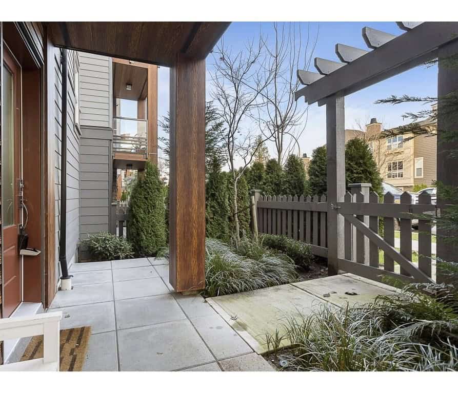 Bright outdoor patio with modern wood and concrete elements, lush greenery, and privacy fencing, perfect for relaxing or entertaining in Vancouver's real estate market.