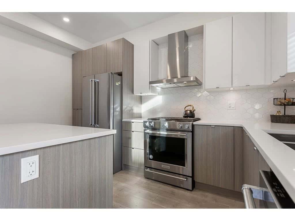 Bright modern kitchen with stainless steel appliances and white hexagon tile backsplash, featuring sleek cabinetry and ample counter space for Vancouver real estate.