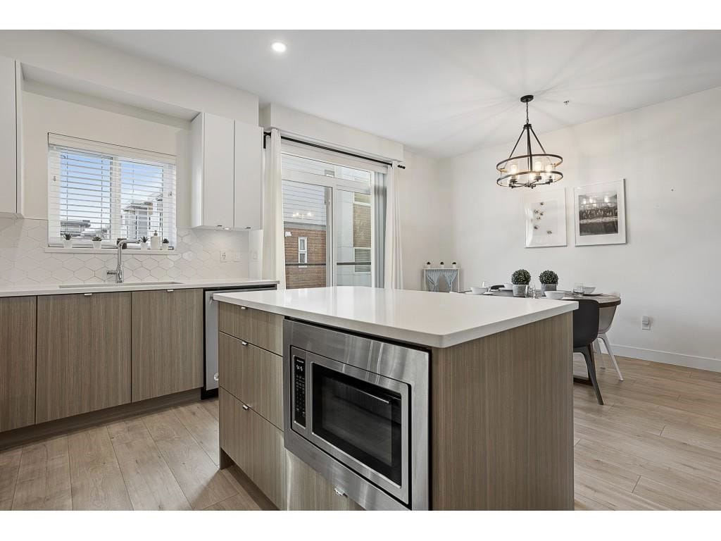 Modern open-plan kitchen with sleek cabinetry, white countertops, and stainless steel appliances in a contemporary residence. Bright, spacious dining area with stylish lighting and minimalist decor.