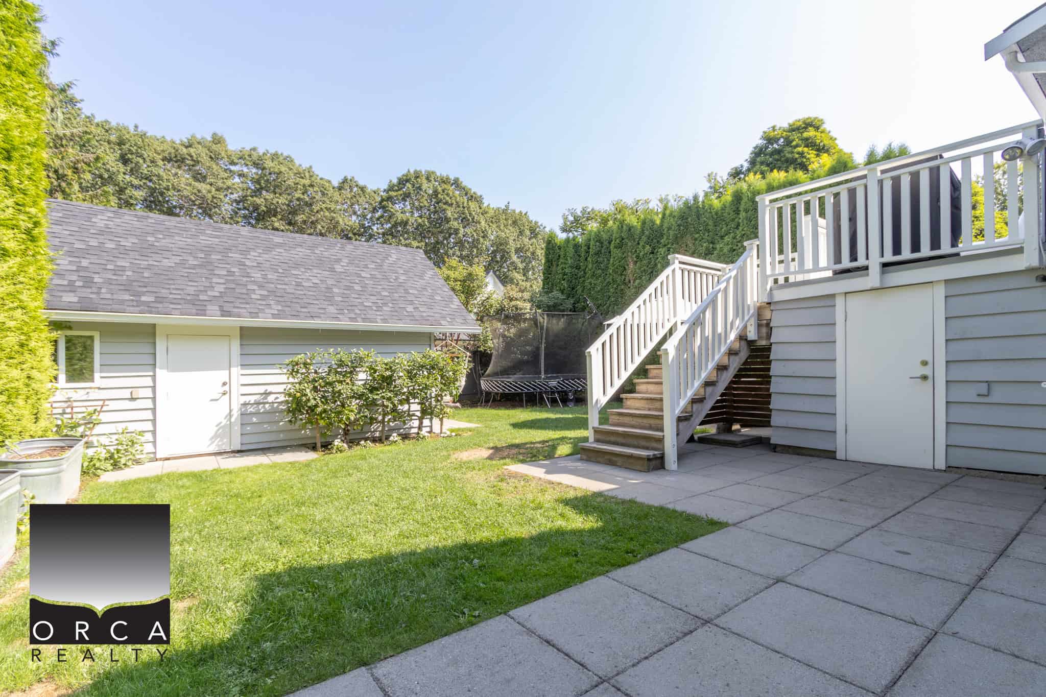 27 Spacious backyard with a wooden deck, staircase, and well-maintained lawn, ideal for outdoor living and entertaining in Vancouver, BC. Perfect for families seeking a serene outdoor space.