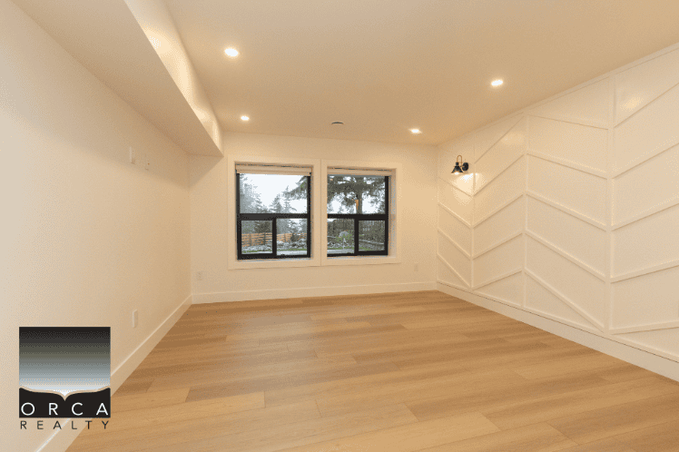 Modern empty living room with large windows and natural light in Vancouver real estate listing.
