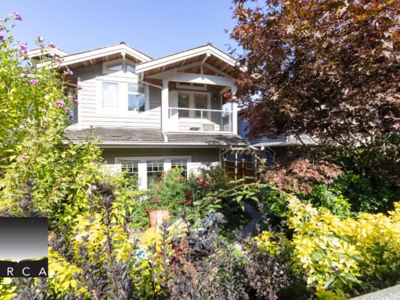 Lush garden with vibrant greenery and flowering plants surrounds a modern two-story home in Vancouver, BC, showcasing desirable real estate options by Orca Realty Inc.