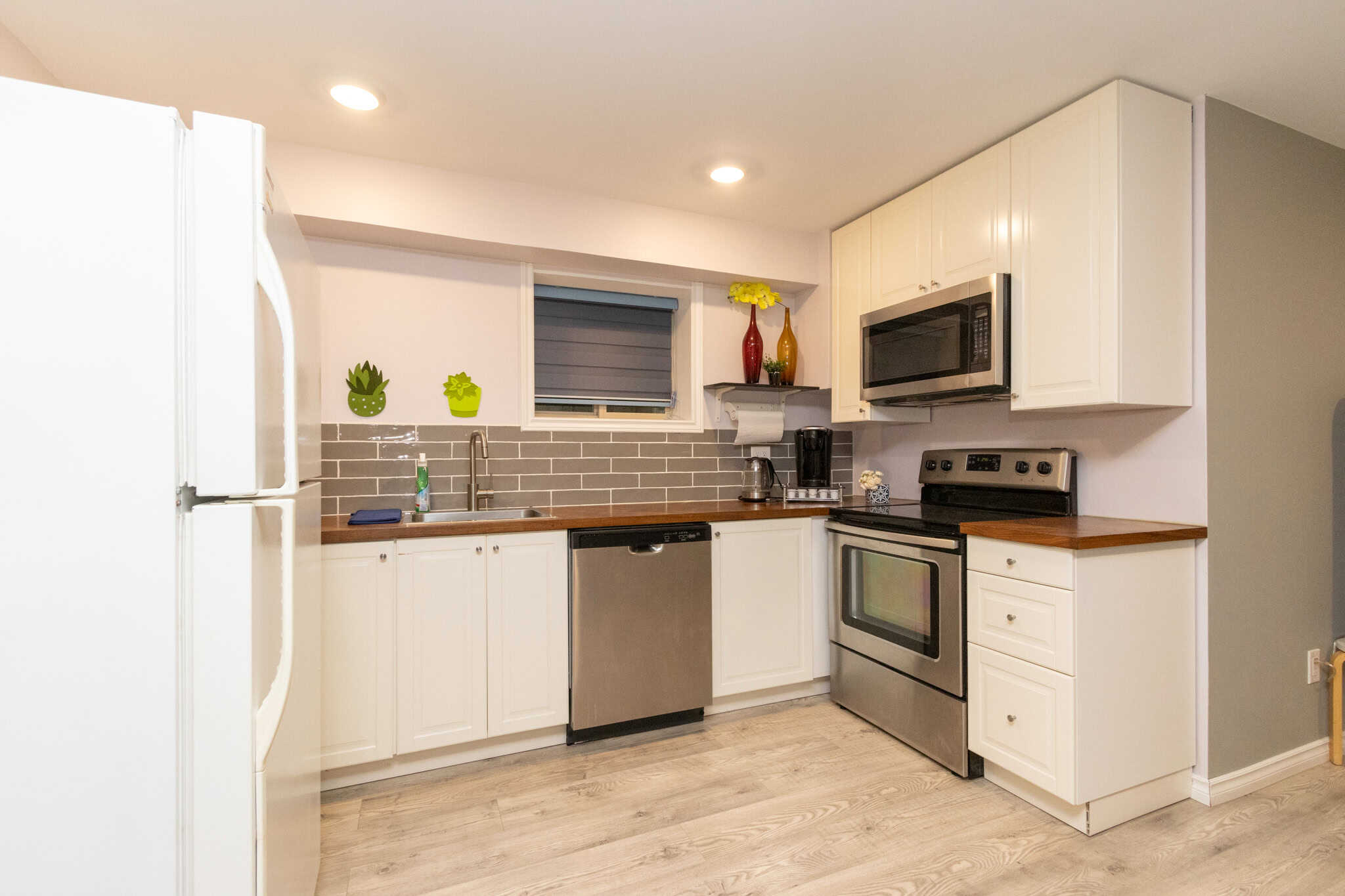 27 Bright modern kitchen with white cabinets, stainless steel appliances, and a gray subway tile backsplash, featuring ample counter space and a cozy window for natural light.