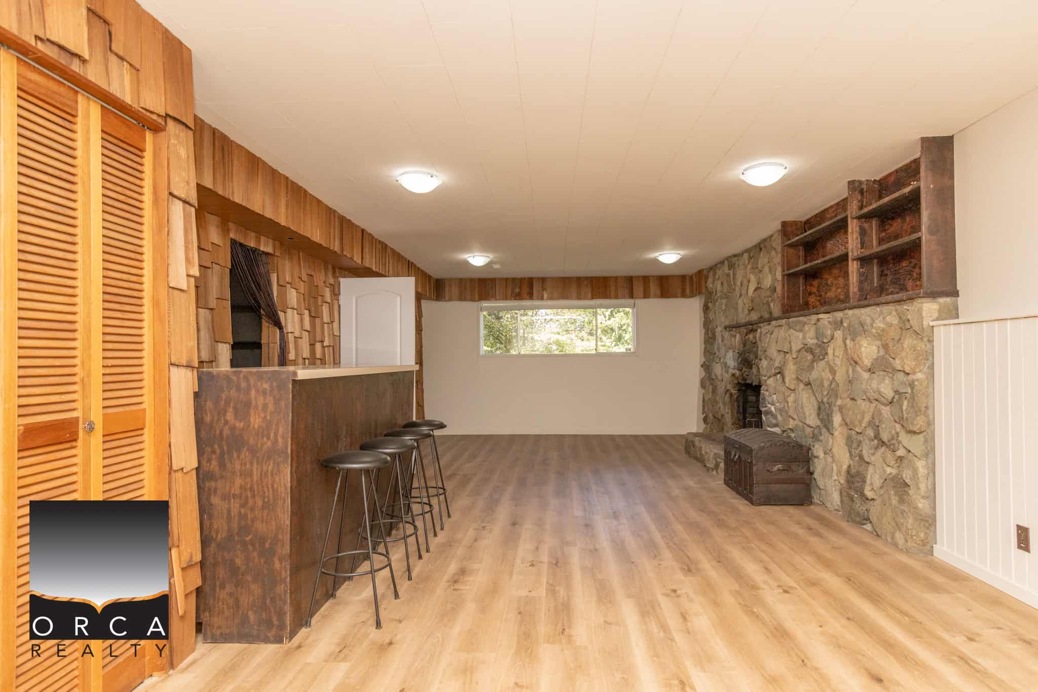 Spacious basement living area with stone fireplace, wood accents, and bar seating, ideal for family gatherings and entertainment in a Canadian home.