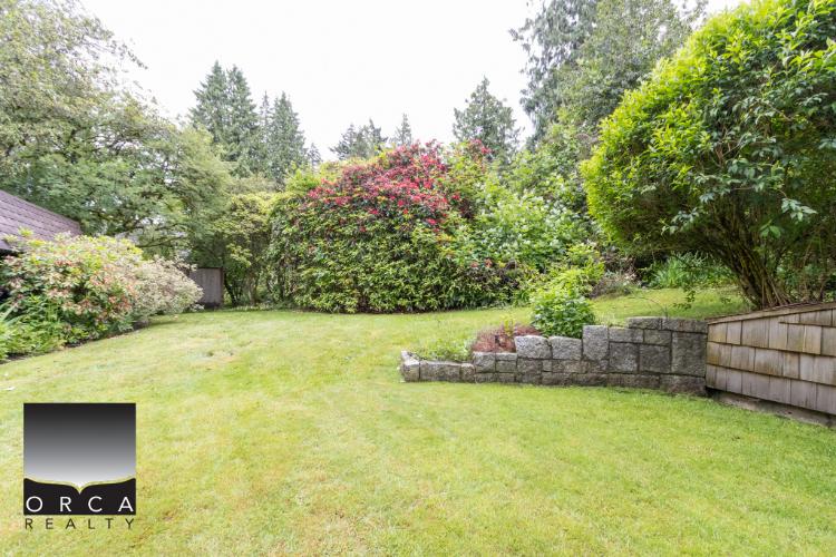 Lush green backyard with well-maintained lawn and vibrant flowering bushes, ideal for outdoor living and gardening, showcasing beautiful home landscaping.