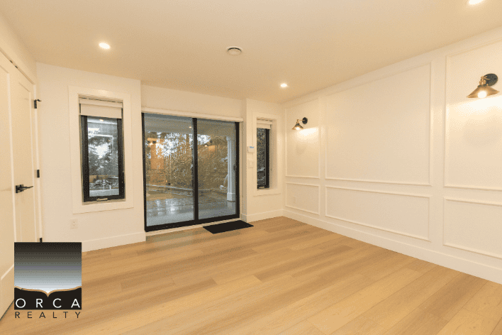 Bright, modern living room with large sliding glass doors, white wall panel accents, and hardwood flooring, perfect for Vancouver area real estate listings.