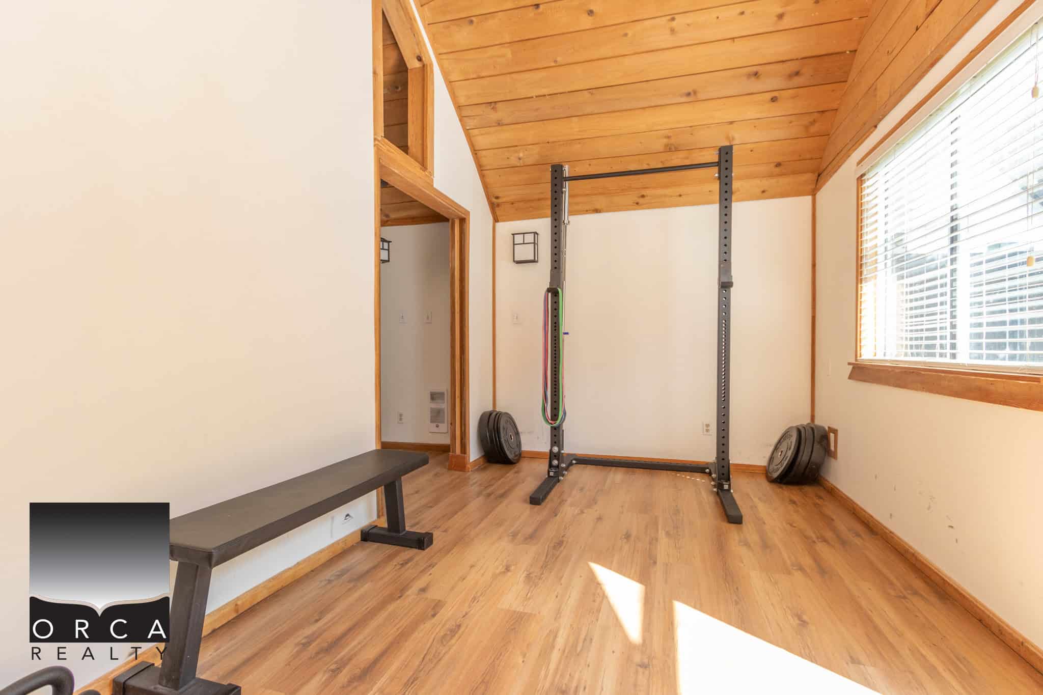 29 Bright home gym space in a modern house featuring wooden accents, workout equipment, and large windows for natural light, perfect for fitness and active lifestyle.