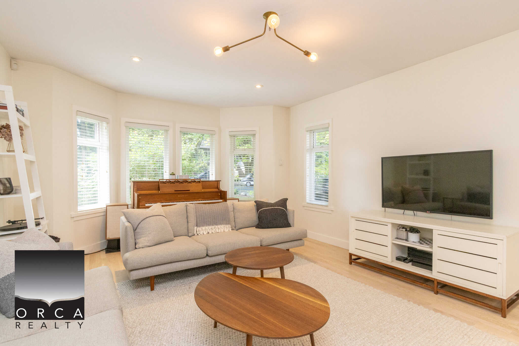 3 Modern living room with bright natural light, white walls, hardwood floors, comfortable sofa, flat-screen TV, and stylish decor, perfect for Vancouver area homes.