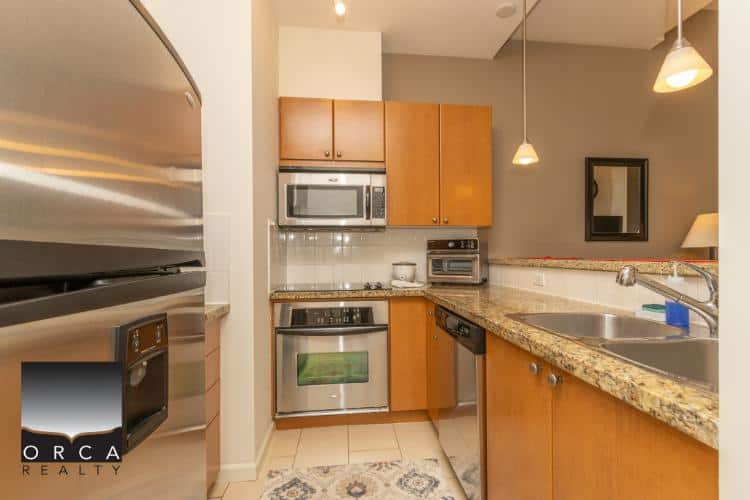 Modern kitchen with stainless steel appliances and granite countertops in a Vancouver condo.