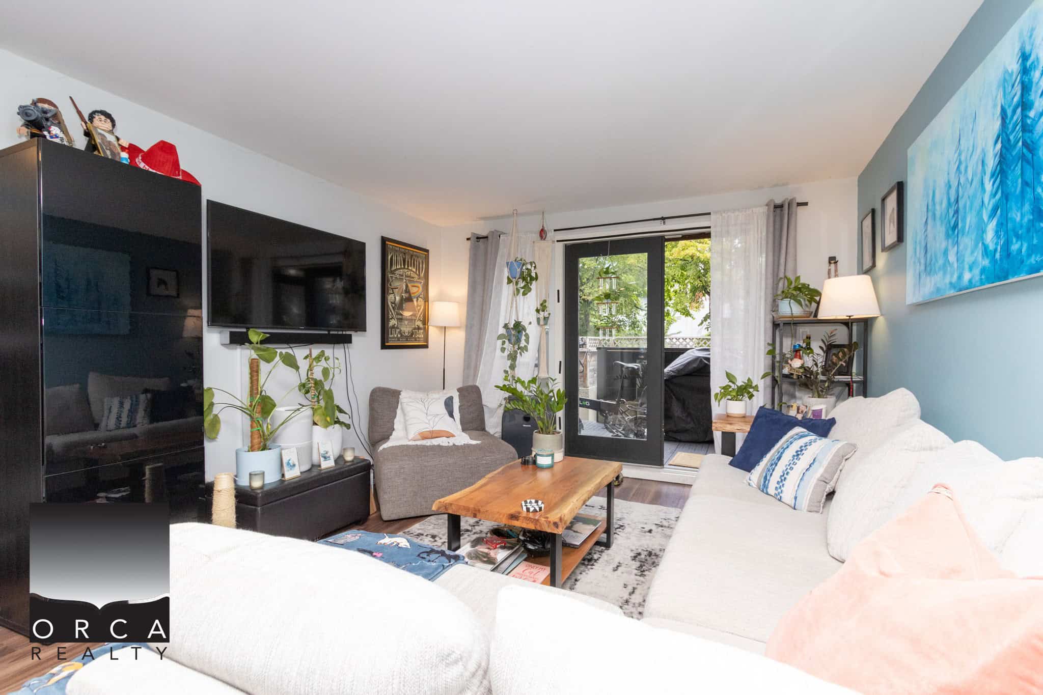 Cozy modern living room with white and blue accents, featuring large window with balcony access, comfy sofas, indoor plants, wall art, and contemporary decor perfect for Vancouver real estate.