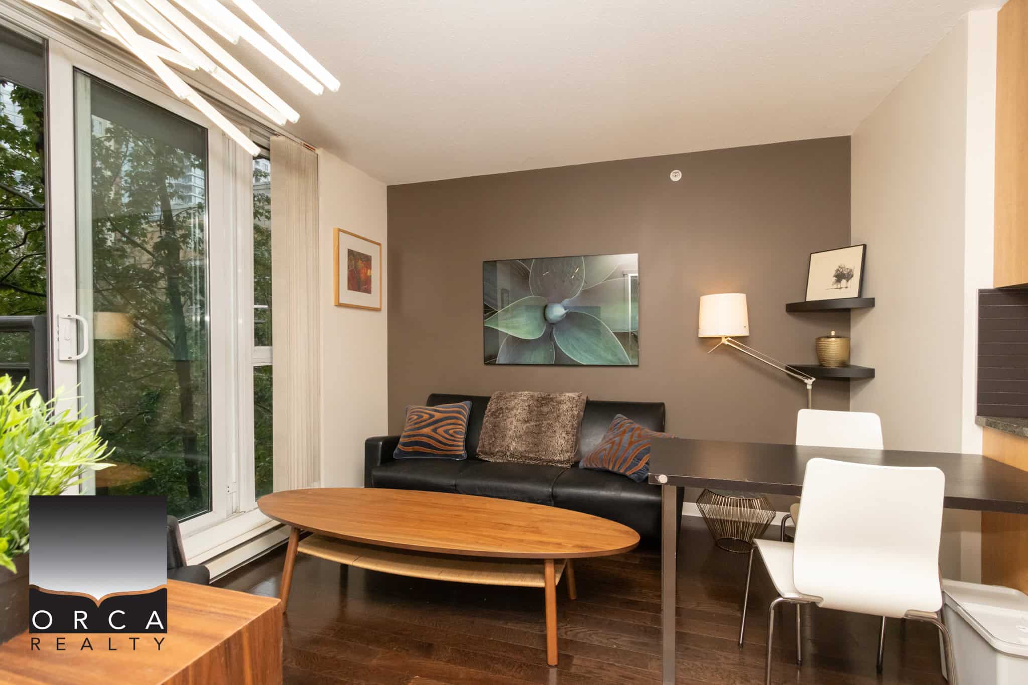 Modern living room with large windows, contemporary decor, and cozy seating area, featured on Orca Realty Inc. website. Perfect for showcasing Vancouver Island properties and real estate opportunities.