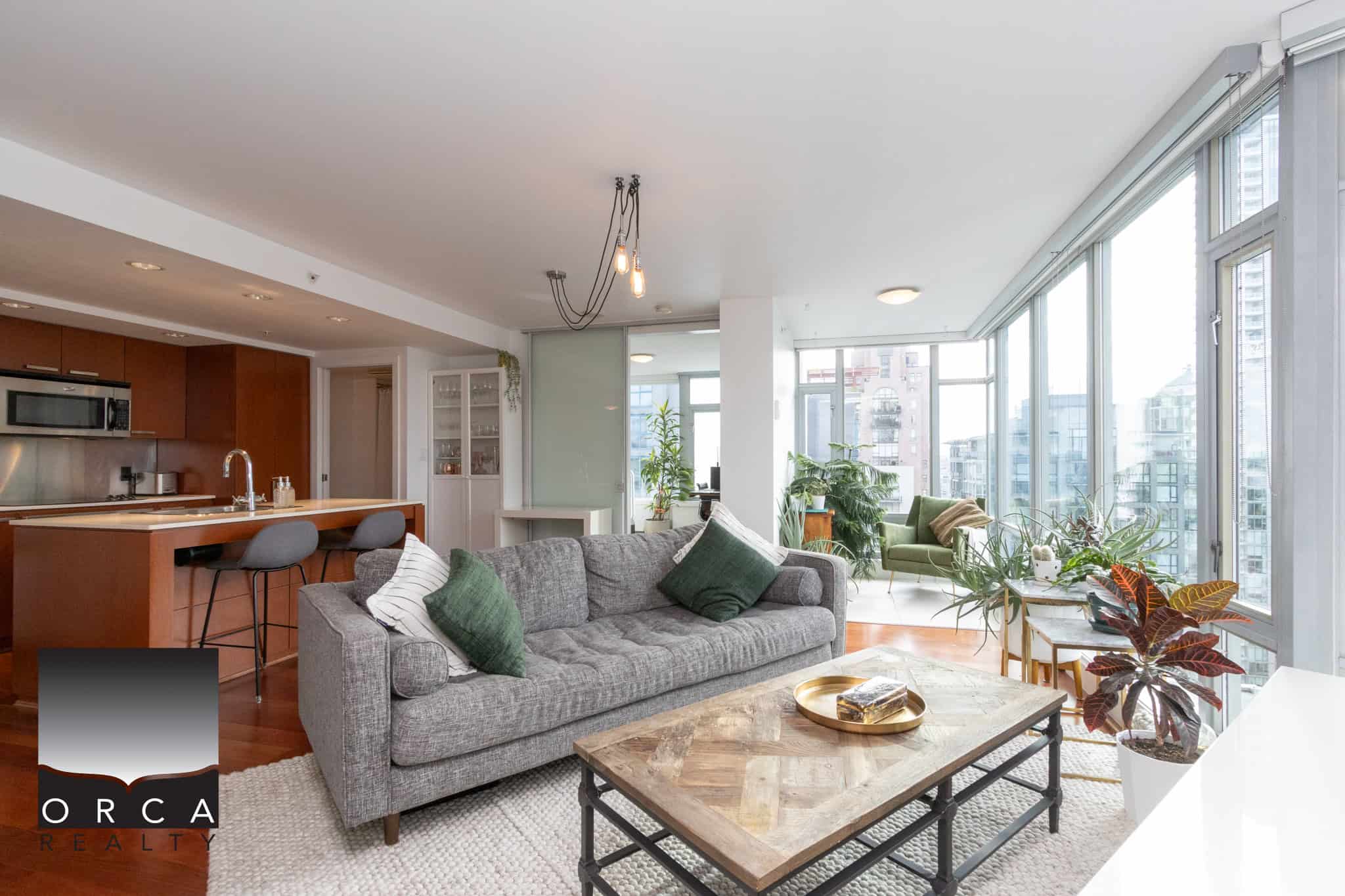 Bright modern condo living room with floor-to-ceiling windows, urban city views, and stylish furnishings, perfect for city living in Vancouver’s vibrant downtown core.