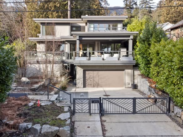 Modern multi-level house with expansive outdoor balcony and scenic mountain views. Features contemporary design, large glass windows, and a spacious driveway, ideal for upscale real estate listings in BC.
