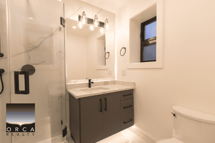 Modern bathroom with shower, vanity, and window at Orca Realty Inc. offers prime Vancouver real estate and property management services. Experience top-rated real estate expertise in BC.