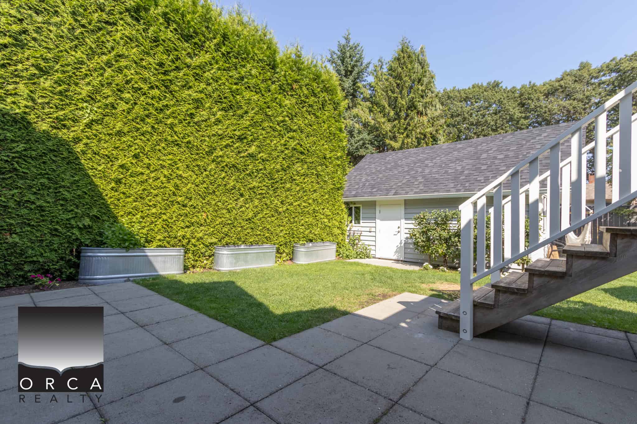 33 Lush backyard with green hedges, metal planters, and a small shed, perfect for outdoor living and relaxation in Vancouver. Ideal outdoor space for homeowners and real estate agents showcasing property features.