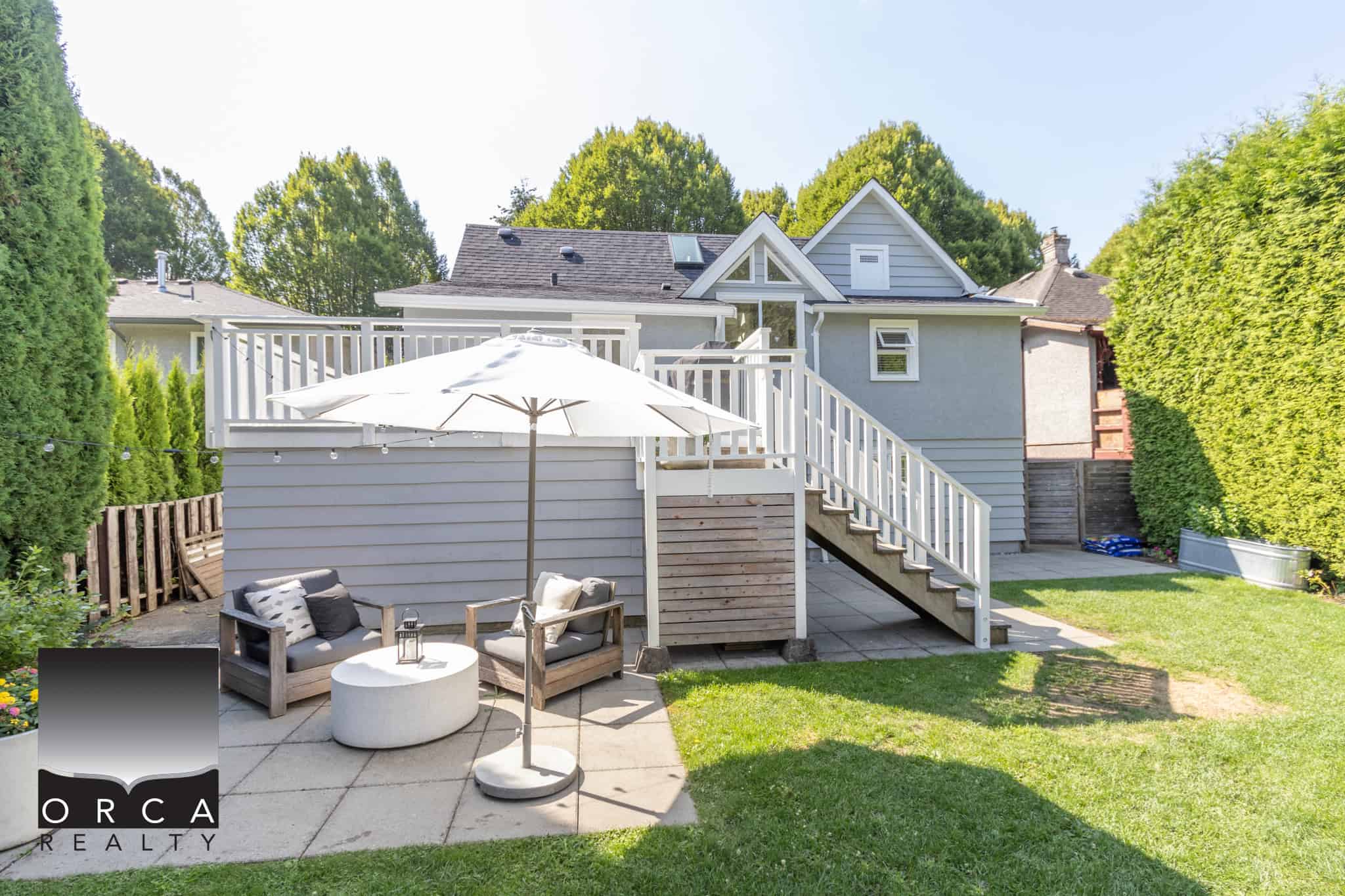 34 Bright outdoor backyard with a cozy patio area, outdoor seating, umbrella, and well-maintained lawn, perfect for relaxing or entertaining guests, showcasing a modern residential property in Vancouver, BC.