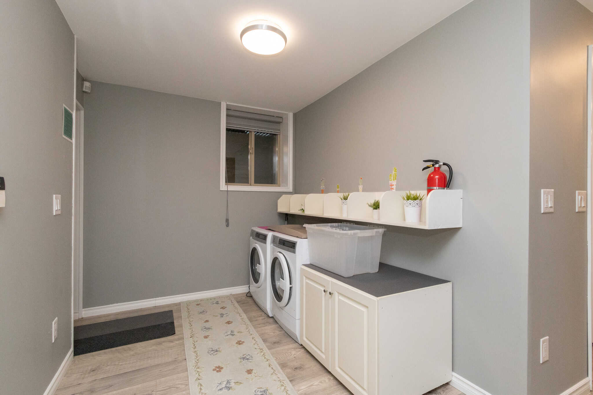 34 Bright laundry room with washer and dryer, grey walls, window, and cabinetry - ideal for Vancouver homes.