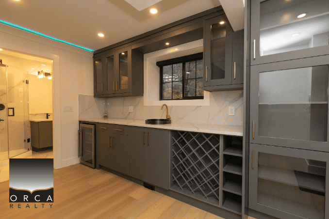 Elegant modern kitchen featuring grey cabinetry, marble backsplash, wine storage, and a large window, ideal for Vancouver real estate listings and residential property marketing.
