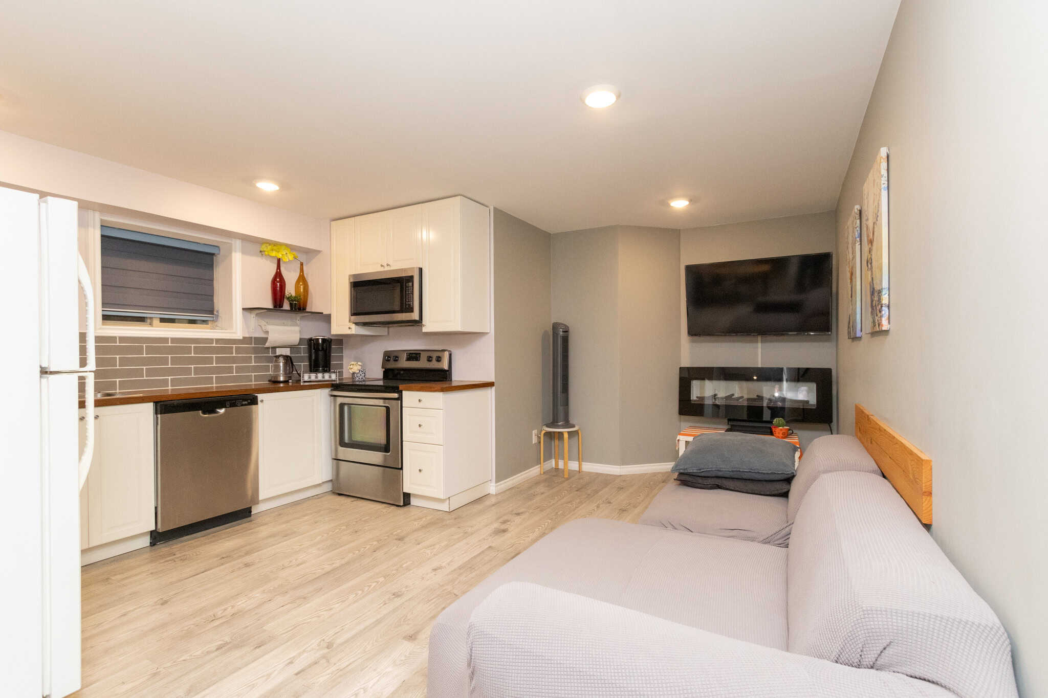 36 Bright open-concept kitchen and living room in a modern Canary Islands style property, featuring stainless steel appliances, a cozy sofa, and contemporary decor, ideal for Vancouver real estate buyers.