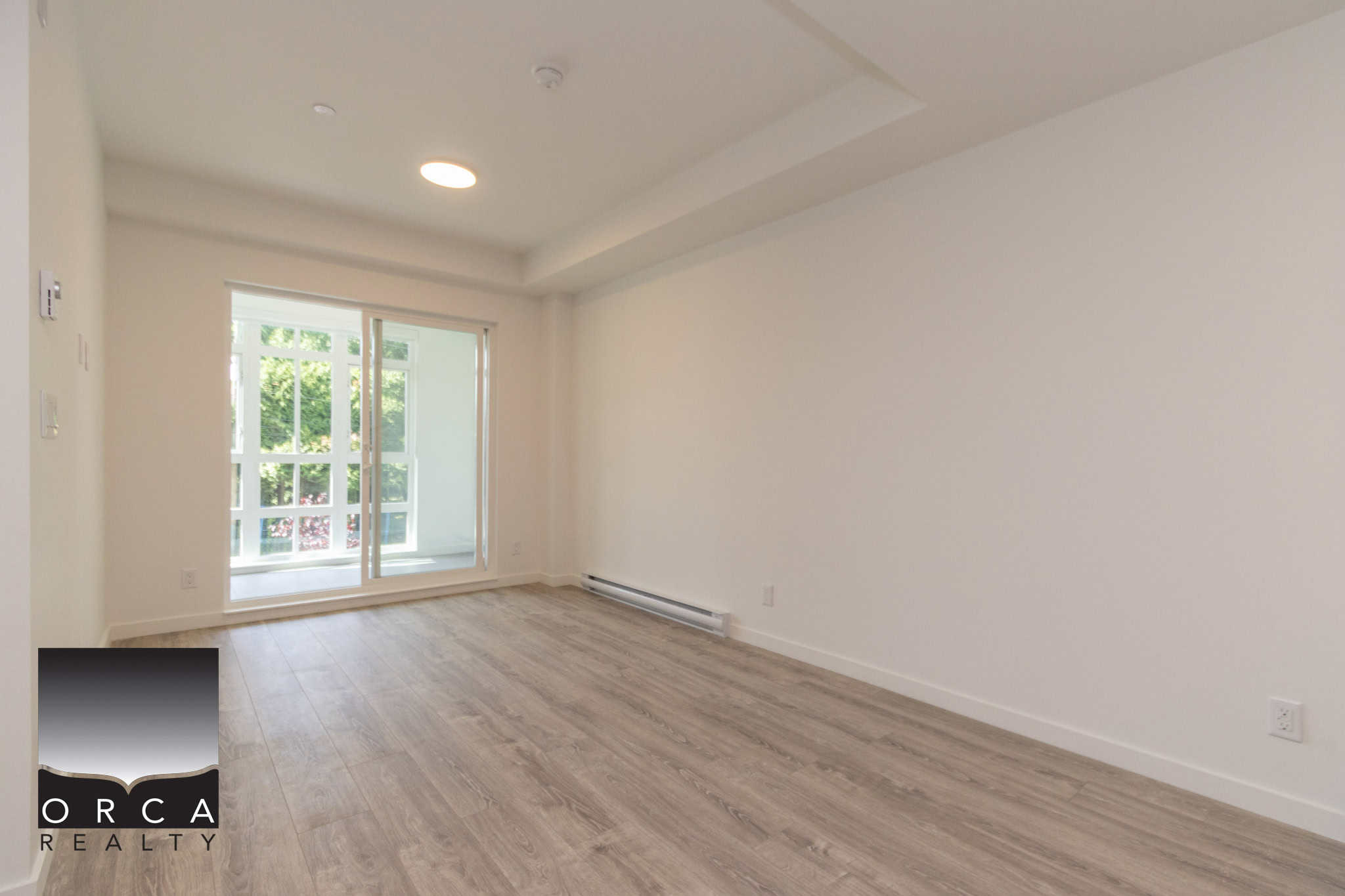 Bright modern living room with large sliding glass door opening to balcony, hardwood floors, and ample natural light, ideal for Vancouver area real estate listings.