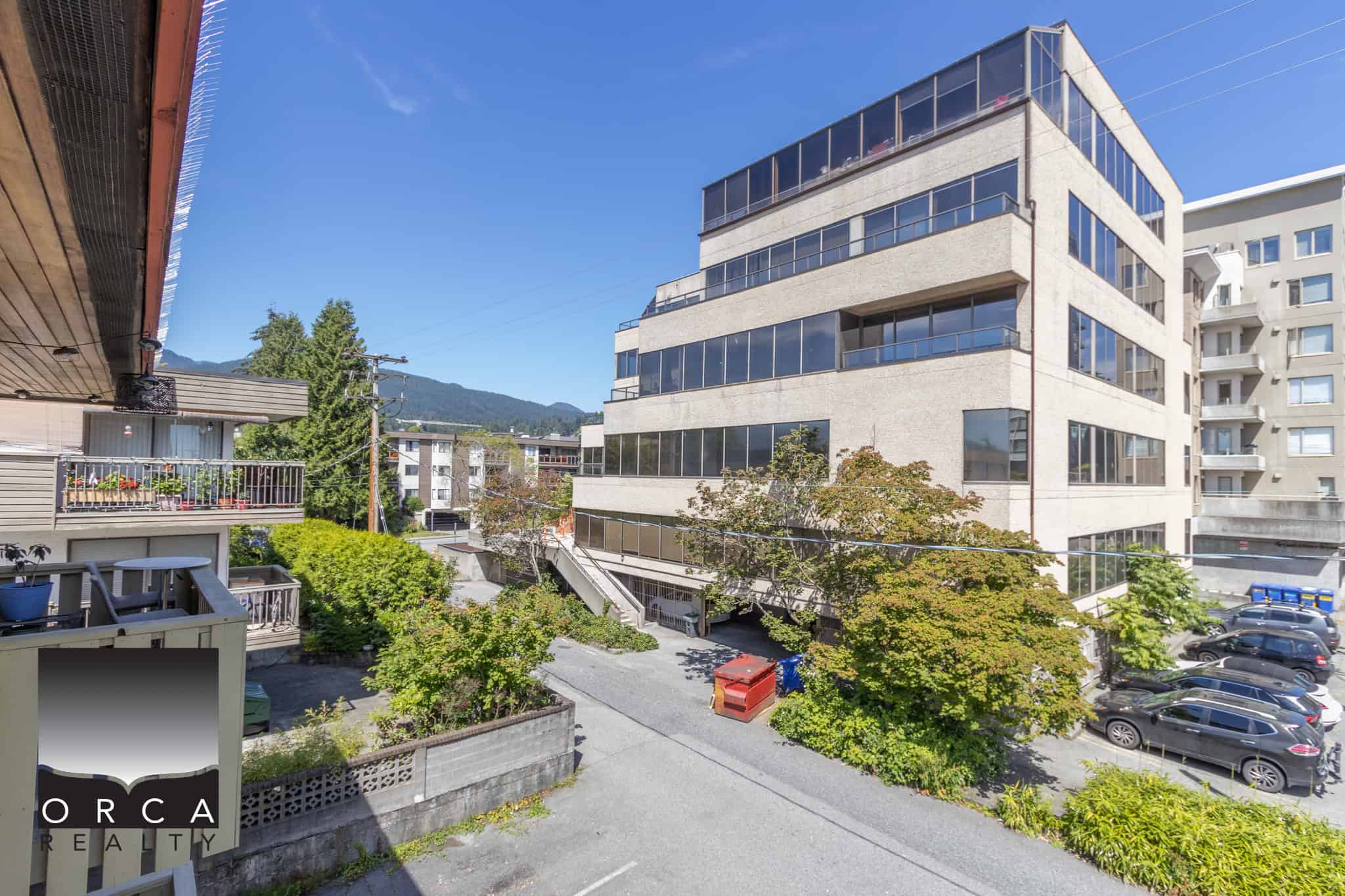 Bright modern office building with large glass windows in downtown setting, surrounded by greenery and parking spaces in Victoria, BC, ideal for commercial real estate investments and business locations.