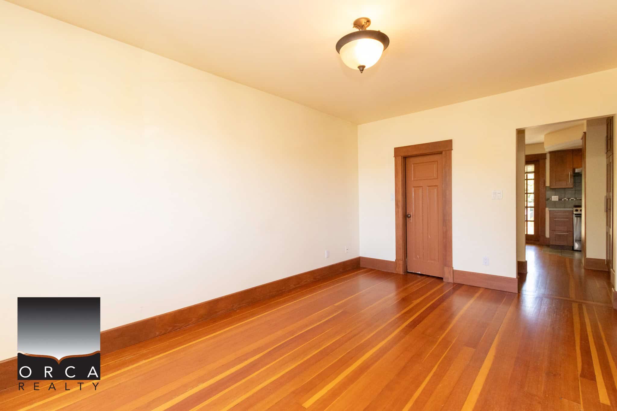 Spacious living room with hardwood floors and natural light, showcasing Orca Realty Inc. property listings and real estate services in BC.