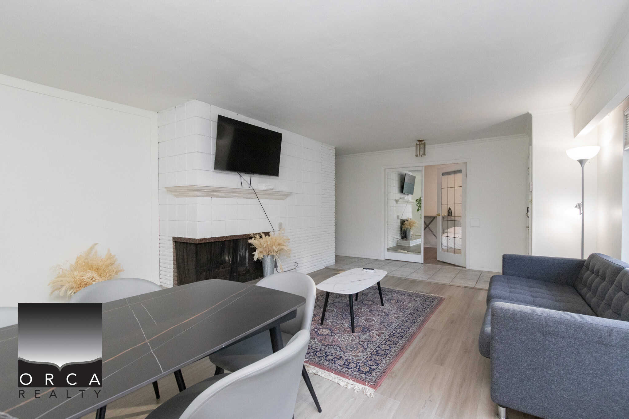 4 Bright Vancouver living room with modern decor, white fireplace, flat-screen TV, and contemporary furniture, showcasing Orca Realty's expertise in Vancouver real estate homes.