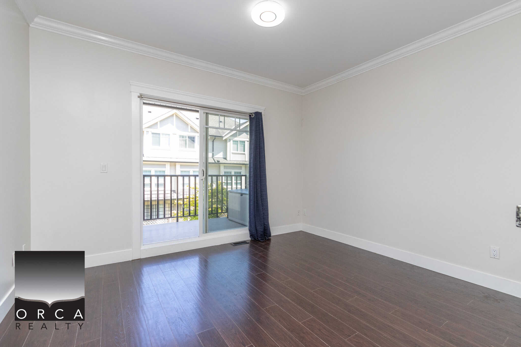 Bright empty living room with sliding glass door leading to balcony in modern residential property for sale or rent in Vancouver, BC.
