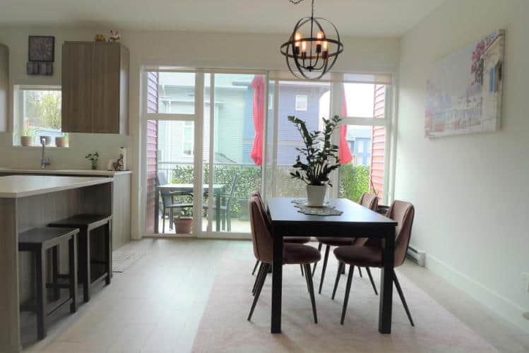 Modern dining area with sliding glass door leading to balcony, featuring contemporary decor and natural light in a Vancouver home.