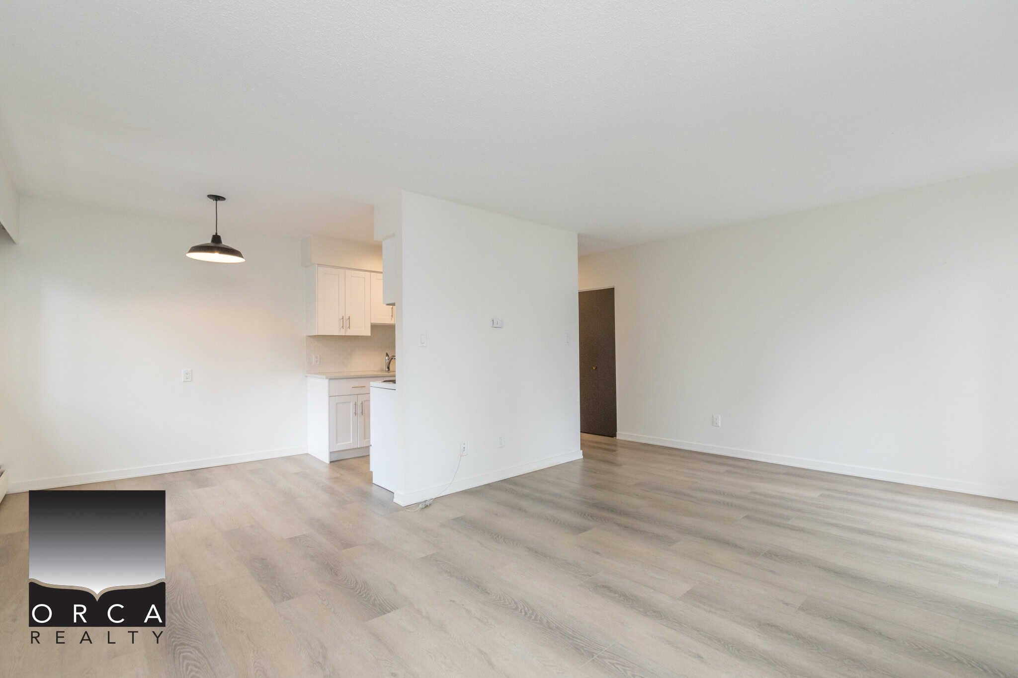 Bright open living space in a modern Toronto condo with hardwood floors and white walls. Fully equipped kitchen and spacious layout perfect for comfortable urban living.