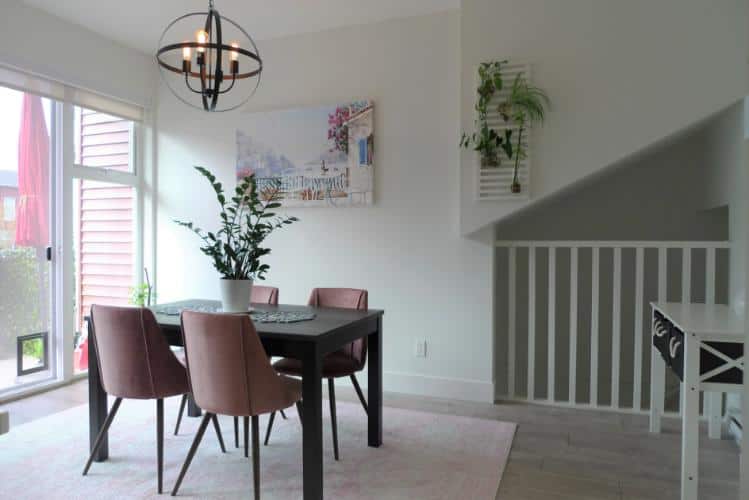 Modern dining room with large window, stylish pink chairs, contemporary decor, and indoor plants, ideal for Vancouver real estate and home staging.