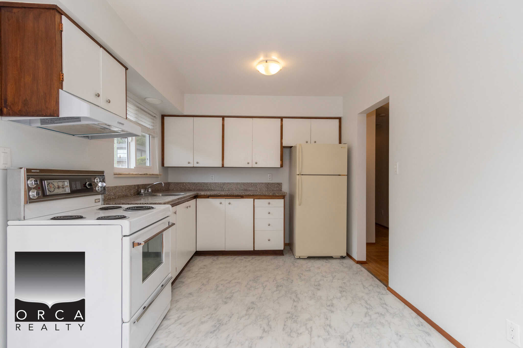 6 Bright kitchen with white and wood cabinets, vintage appliances, and natural light, perfect for Vancouver property buyers seeking a cozy, functional space in the Orca Realty real estate listings.