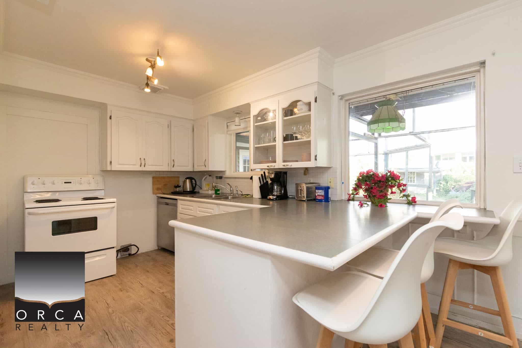 6 Bright white kitchen with natural sunlight, modern appliances, and cozy dining area showing a welcoming space for family living and urban home comfort in Victoria, BC.