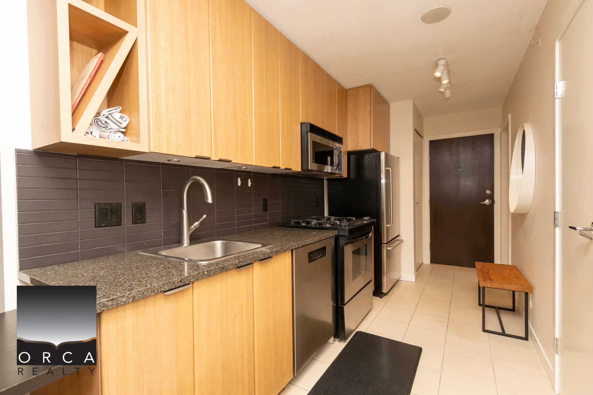 Modern kitchen with stainless steel appliances, wooden cabinets, granite countertops, and a dark tile backsplash, perfect for Vancouver Island real estate buyers.