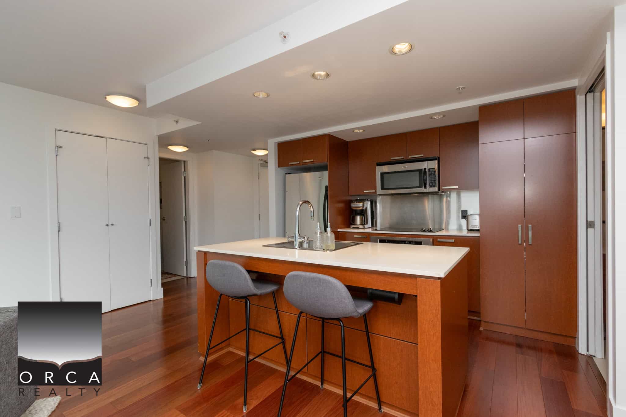 Modern kitchen with contemporary cabinets, stainless steel appliances, and a spacious white island perfect for dining and entertaining in a Vancouver condo.