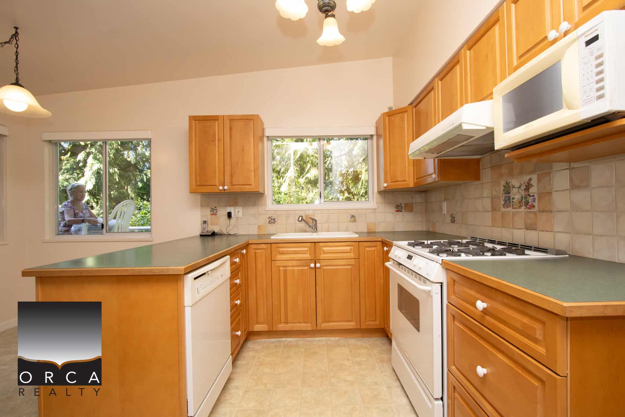 Clean and functional kitchen in a Vancouver home featuring natural wood cabinets, modern appliances, and a bright window view of lush greenery, perfect for Vancouver real estate listings.