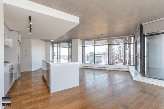 Spacious modern apartment living room with large windows, hardwood floors, and open-concept kitchen in downtown Vancouver. Perfect for urban living and real estate investment.