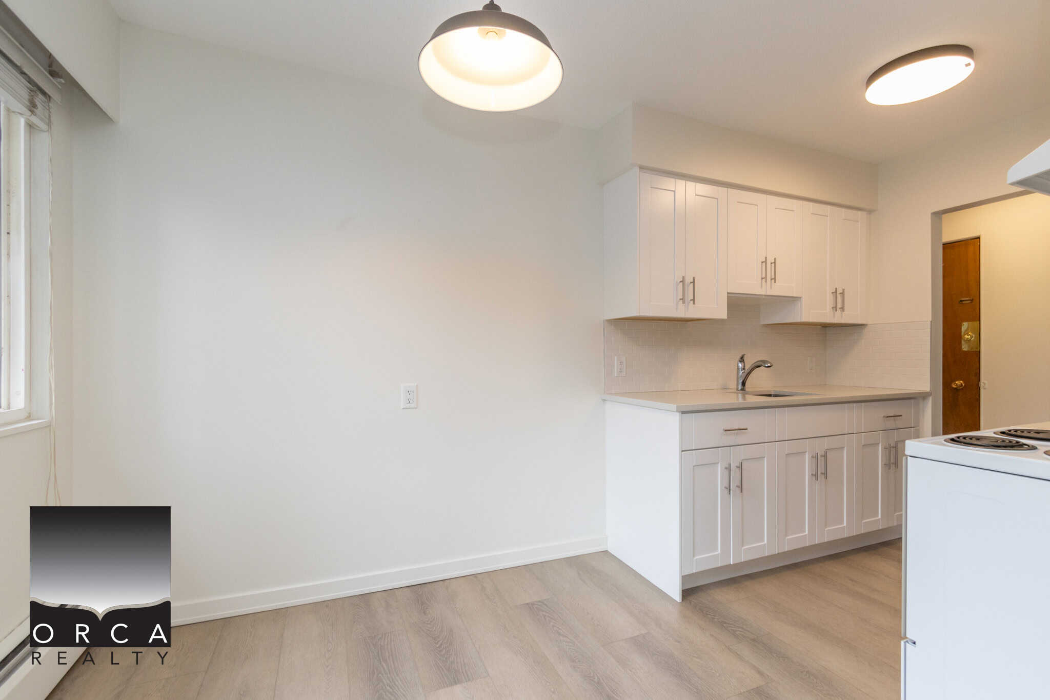 Bright white kitchen with modern cabinets and wood flooring, ideal for Vancouver Island real estate listings.