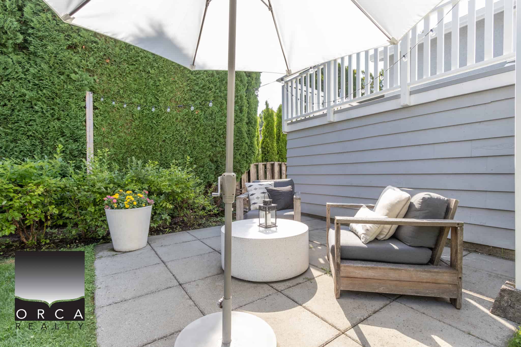 7 Modern outdoor patio with comfortable seating, lush greenery, and decorative string lights, ideal for outdoor living and entertaining in Vancouver Island homes.