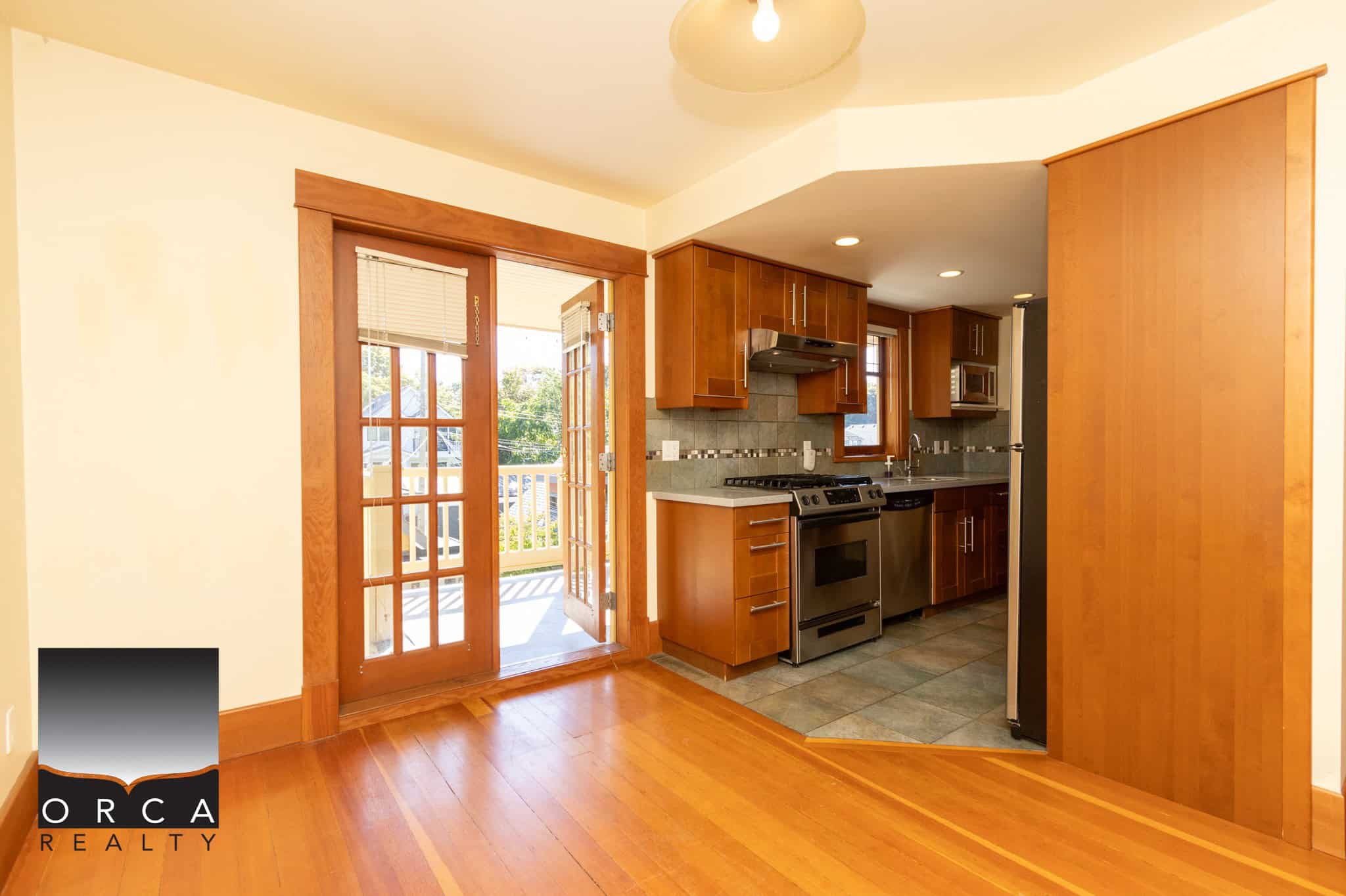Bright open-concept kitchen with wooden cabinets, stainless steel appliances, and access to outdoor patio, ideal for Vancouver Island real estate properties.