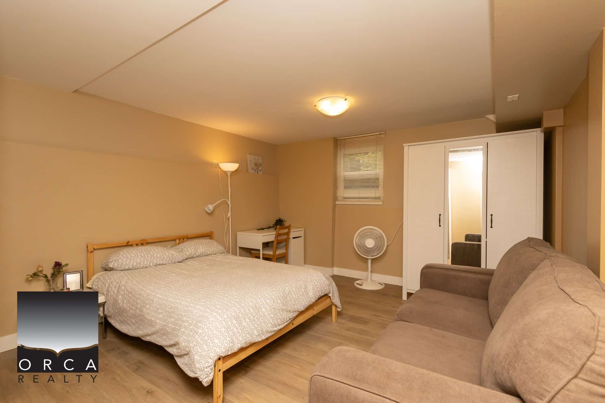 Cozy bedroom interior in a modern apartment or condo, featuring a comfortable bed, white wardrobe, sofa, and soft lighting, ideal for Vancouver real estate listings, rentals, or property marketing.