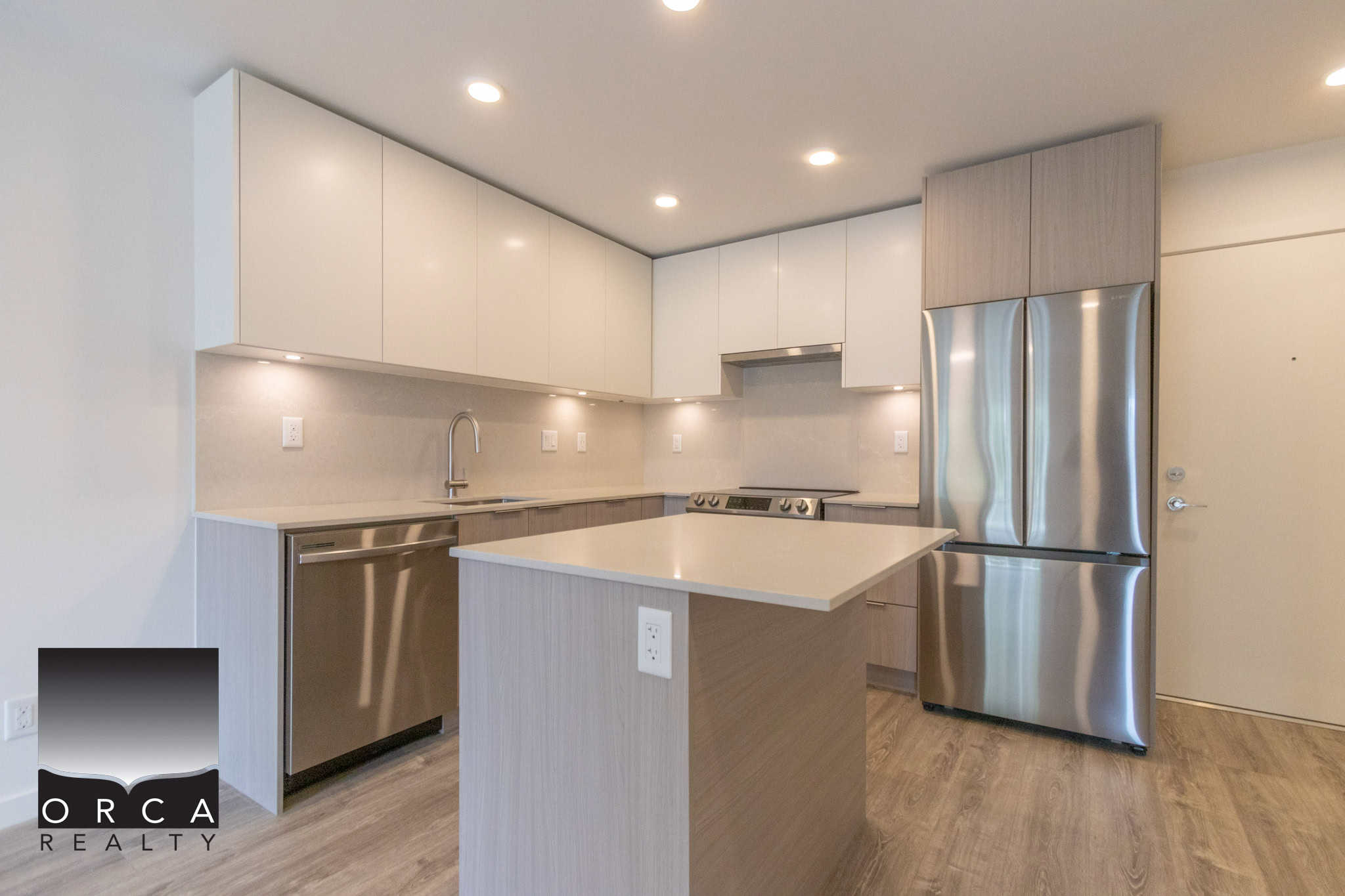 Bright modern kitchen with stainless steel appliances and white cabinetry, featuring a spacious island, ideal for Vancouver Island real estate and homebuyers seeking contemporary homes.