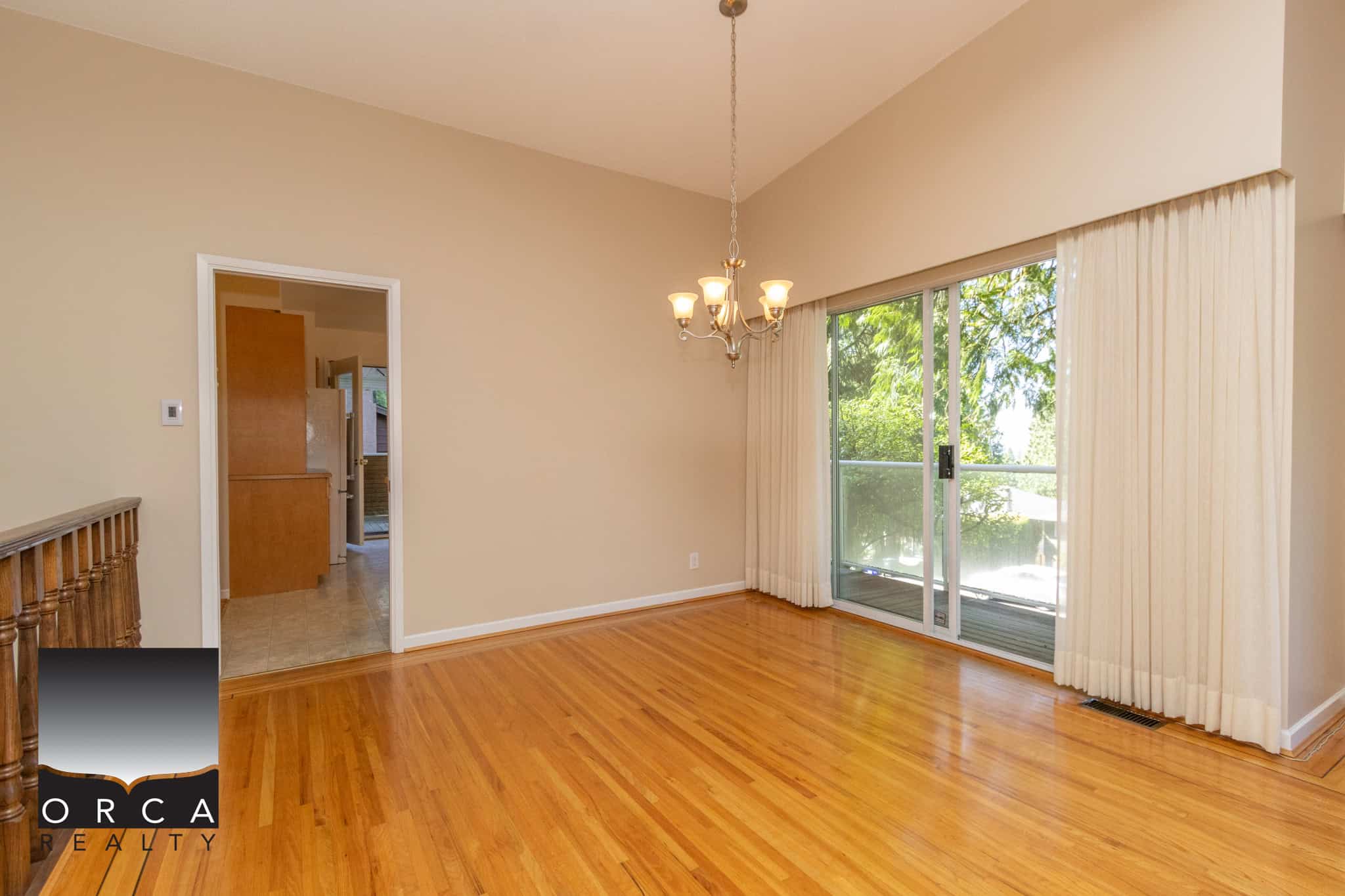 Spacious dining area with hardwood floors, large sliding glass doors, and elegant chandelier, perfect for homebuyers seeking affordable real estate in Vancouver area.