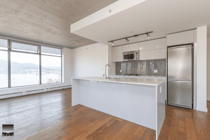 Bright modern kitchen with stainless steel appliances in a downtown Vancouver condo featuring large windows and open concept living space.