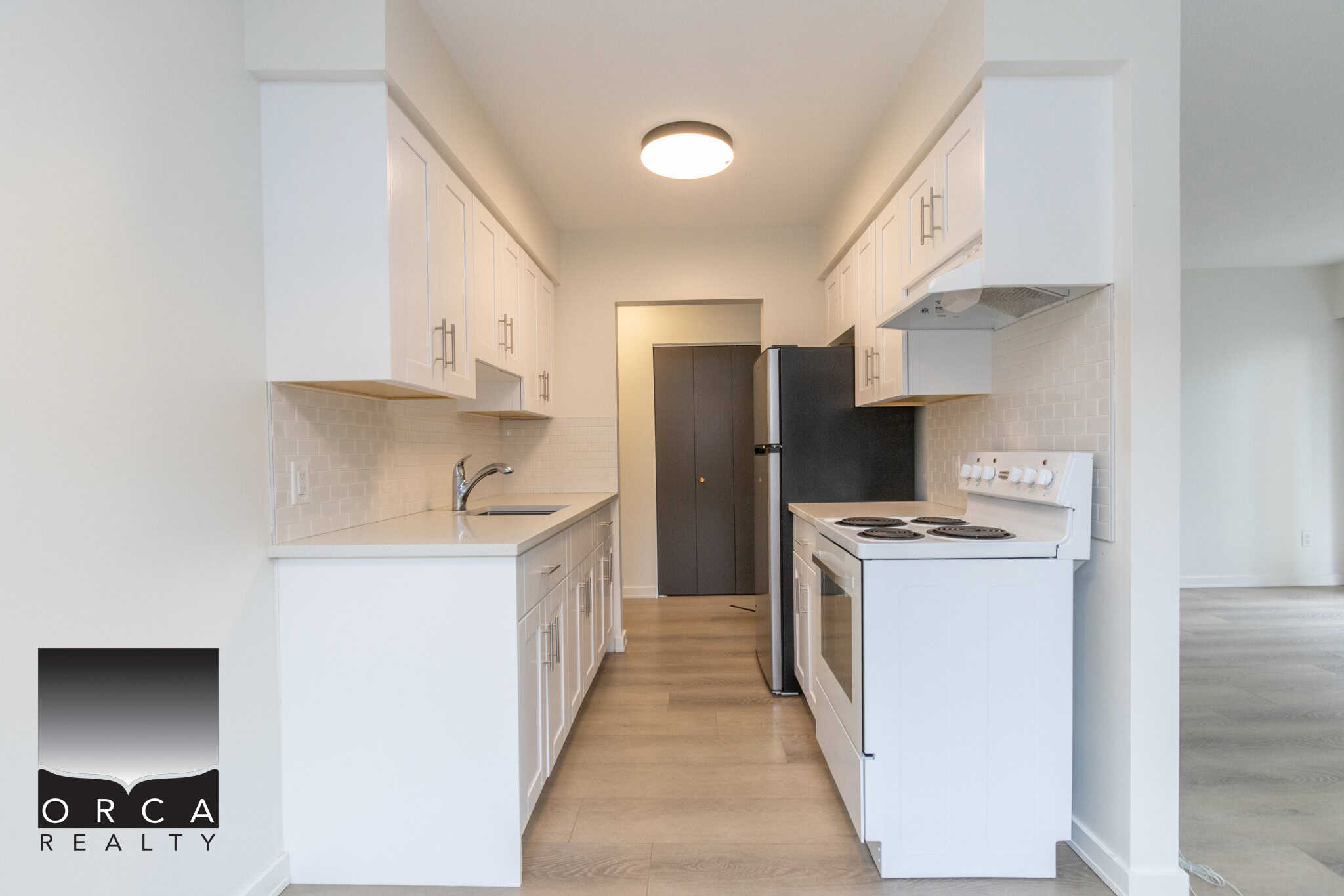 Modern white kitchen with a minimalist design, featuring white cabinets, a sleek countertop, and essential appliances for a functional and stylish kitchen space.