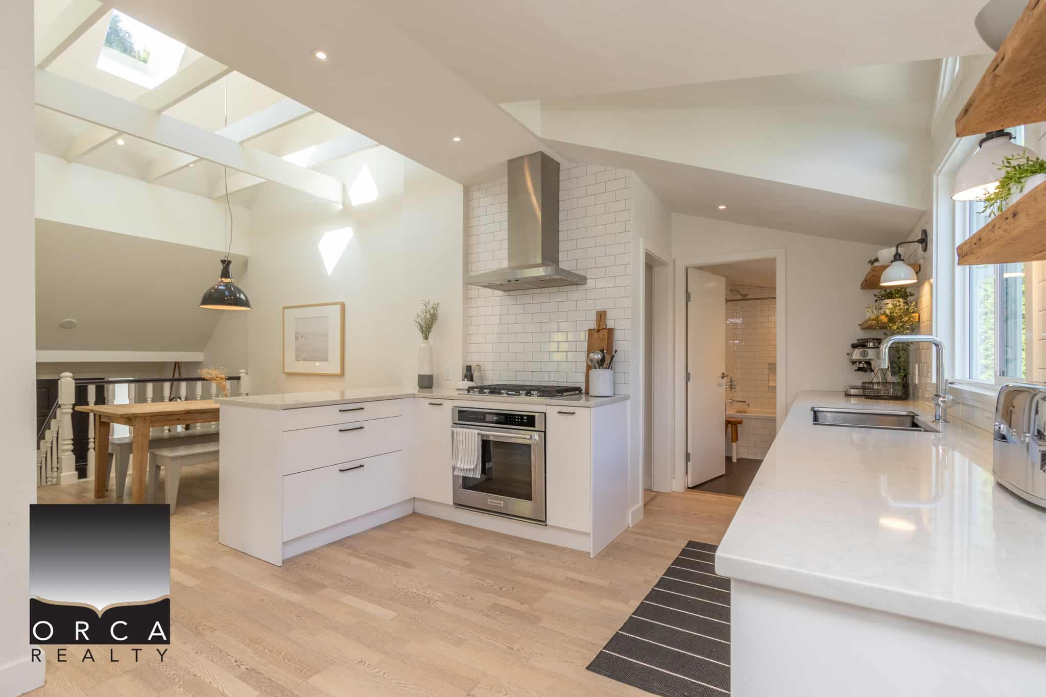 8 Bright modern kitchen with white cabinetry, natural light, and sleek appliances in a stylish home listed by Orca Realty Inc. Vancouver Island real estate experts.