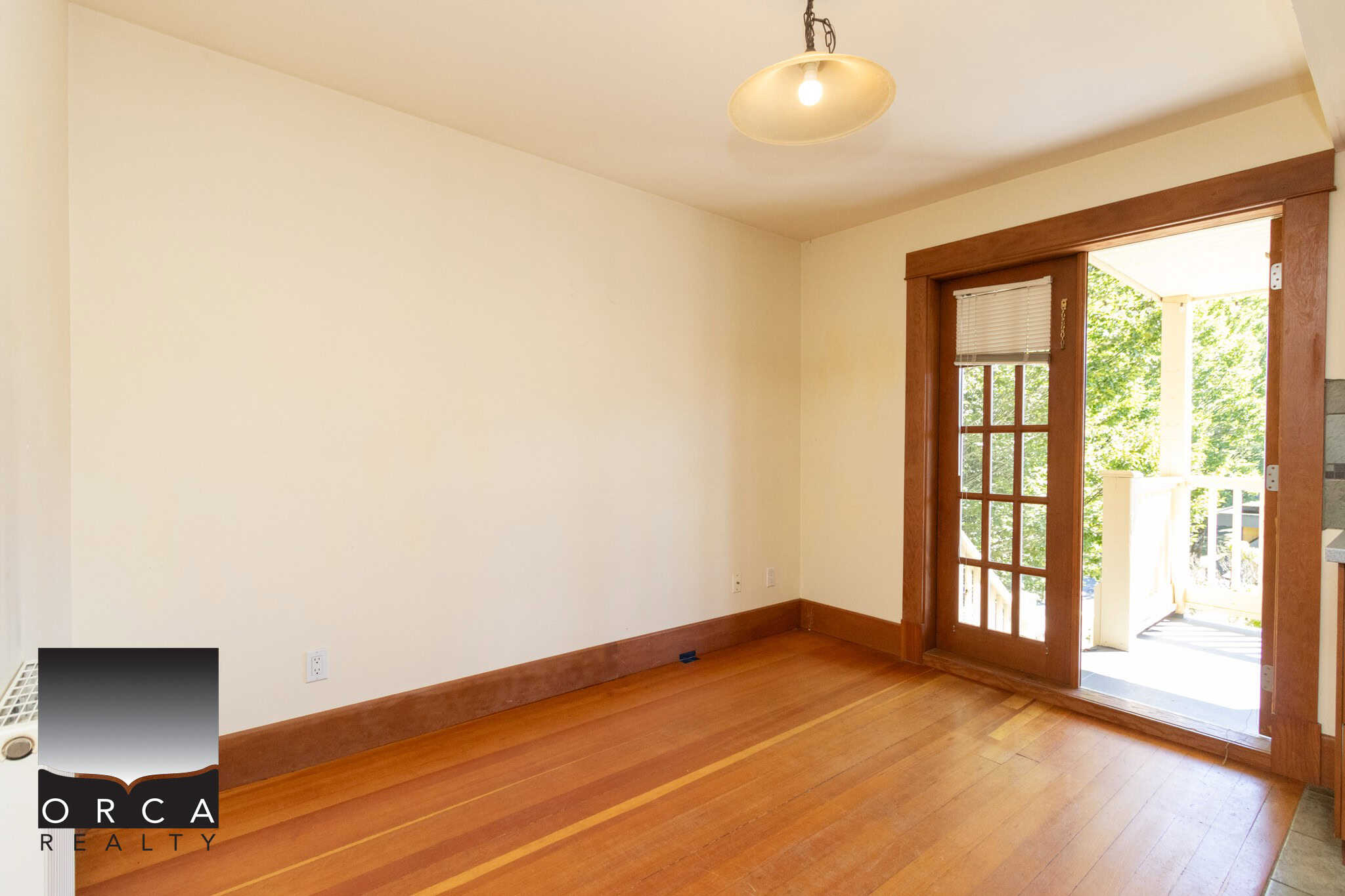 Bright living room with hardwood floors, large glass door leading to balcony, natural light, ideal for Vancouver area homes, by Orca Realty Inc.