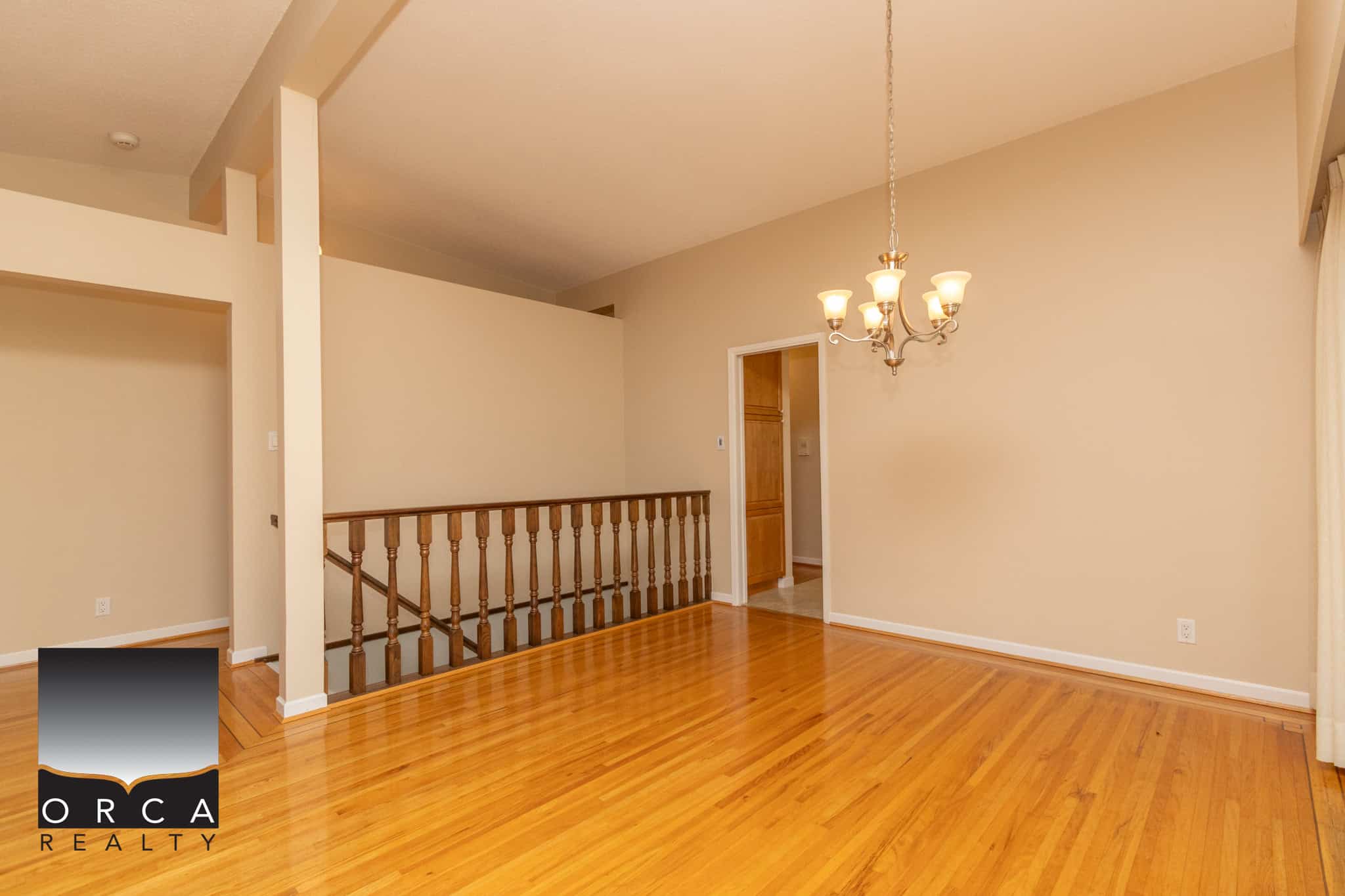 Spacious dining area with hardwood floors and a chandelier, showcasing a warm, inviting interior space ideal for family gatherings and entertaining in a home listed by Orca Realty Inc.