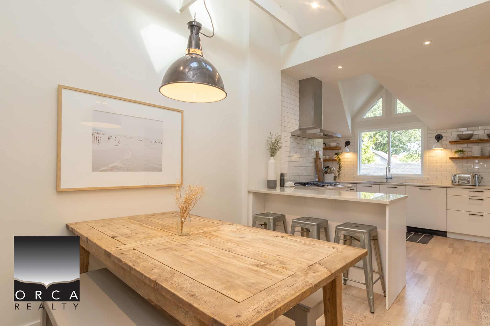 9 Bright, modern kitchen and dining area with natural lighting, white cabinetry, wooden accents, and stainless steel appliances, perfect for stylish Vancouver Island living.